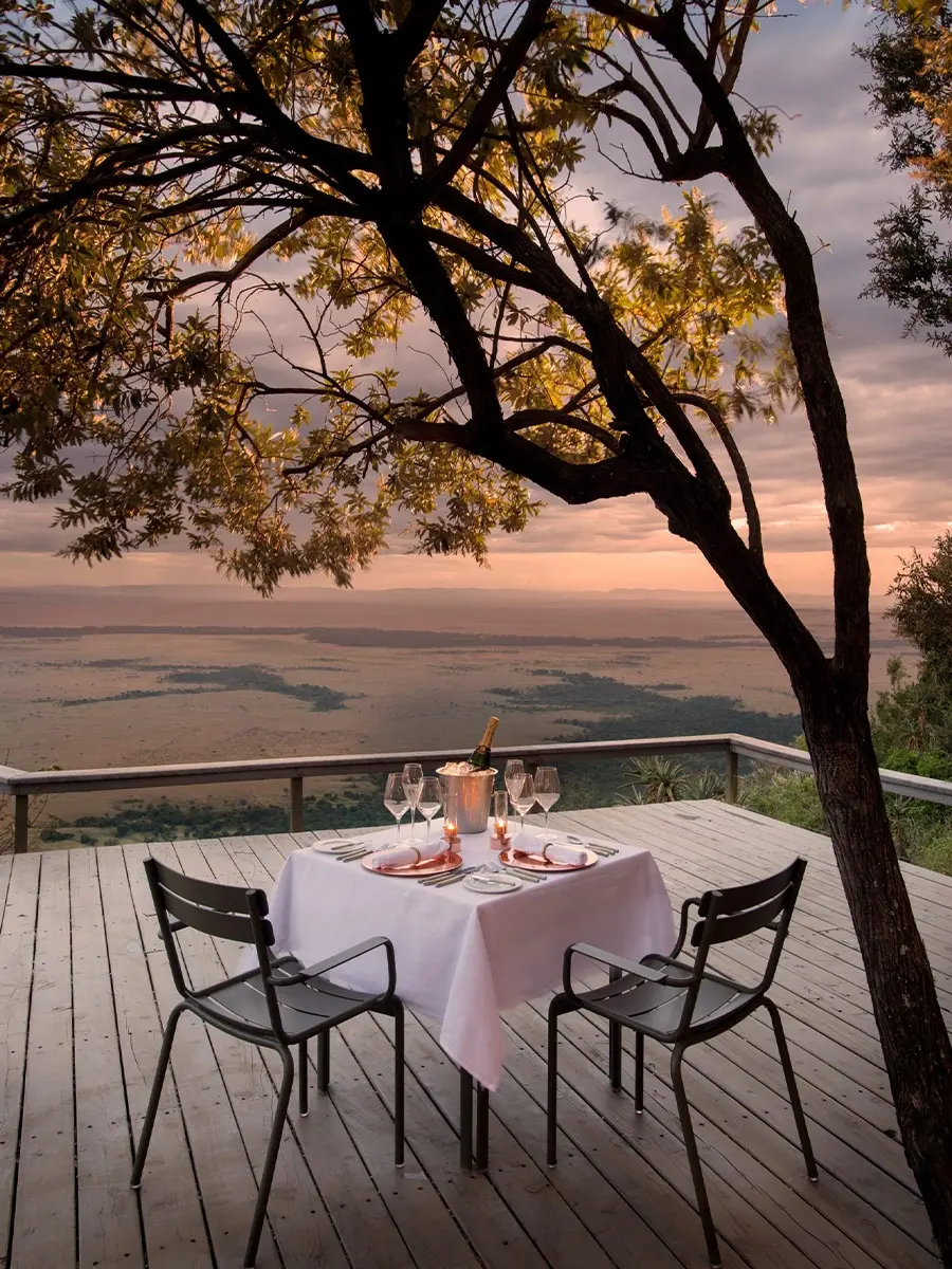 A candlelit table for two on a deck beneath an acacia at sunset